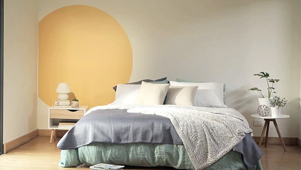 un muro interior pintado con figuras geom&eacute;tricas con una mesa de arrimo y una silla